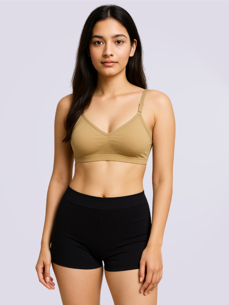Woman wearing a beige sports bra and black shorts on a light gray background